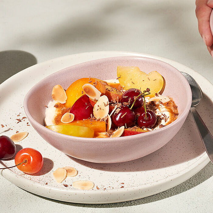 Frische Früchte wie Kirschen, Aprikosen und Äpfel mit cremigem Brunch kombiniert in einer Bowl