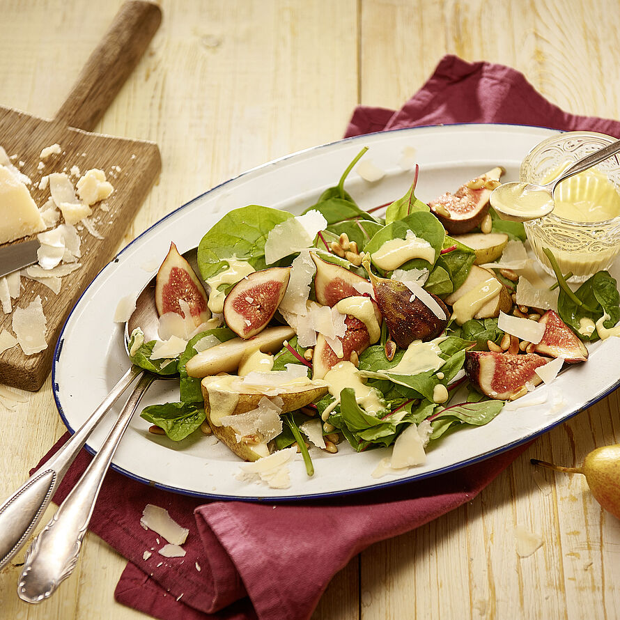 Außergewöhnlicher Salat mit Birne, Feigen und Brunch „Zarte Blüte auf einem ovalen weißen Salatteller serviert