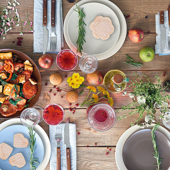 Bunt dekorierter Tisch zum Frühlingsanfang mit Blumen, Obst und Gemüse