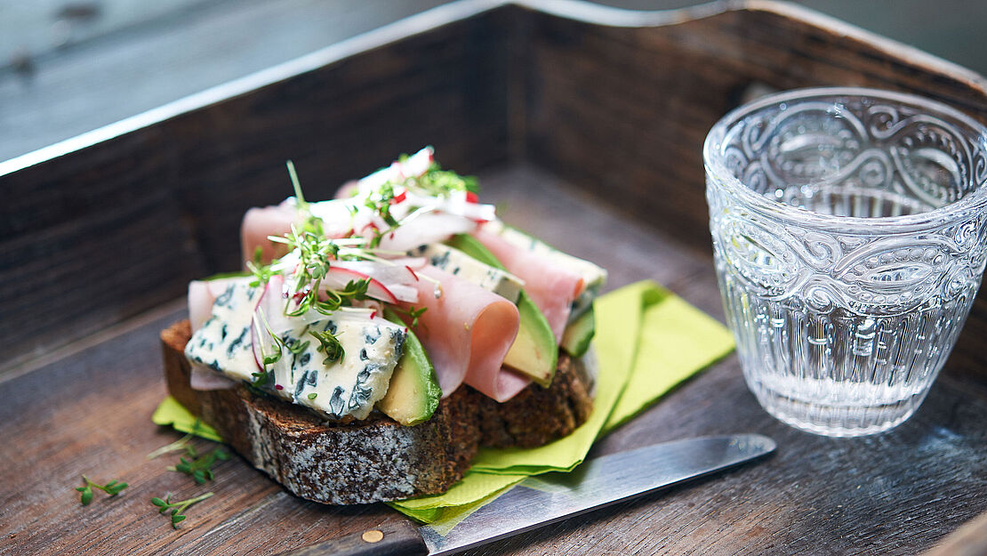 Rustikales Vollkornbrot mit Schinken, frischer Avocado und würzigem Saint Agur L&#039;Intense Käse