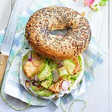 Ein appetitlicher Bagel, der mit cremigem Frischkäse bestrichen wurde. Belegt mit Salat und Hühnchen