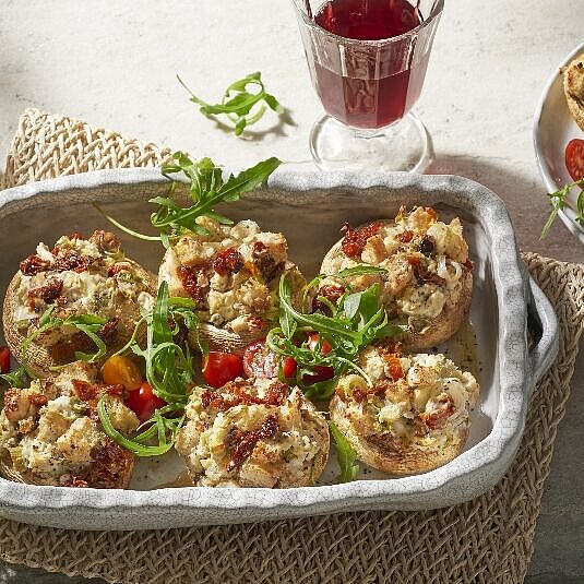 Teller mit saftigen, gebackenen Champignons, gefüllt mit cremigem BRESSO. Der Käse ist goldbraun gebacken.