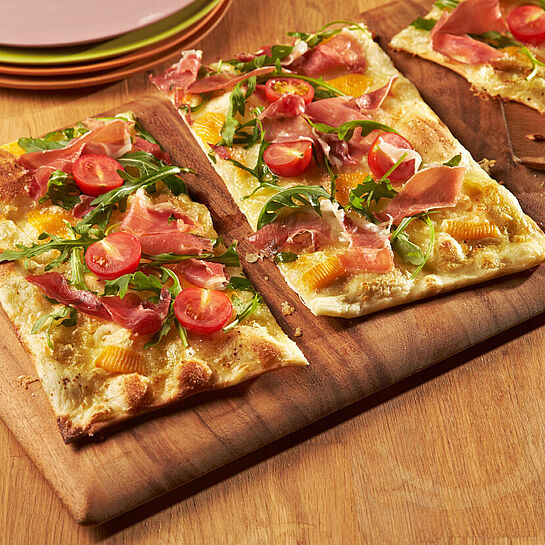 Frisch aus dem Ofen: Herzhafter Flammkuchen mit Rucola und Schinken.