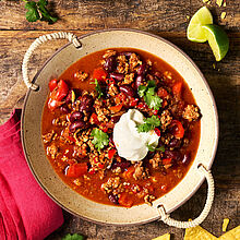 Rustikales Chili con Carne auf klassische Art in einer großen Schüssel mit Griffen. Getoppt mit Brunch Frischkäse