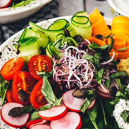 Mediterrane Couscous-Bowl mit Babyspinat, Sproßen, Tomaten, Radieschen, Gurken, Kürbiskernen und mehr