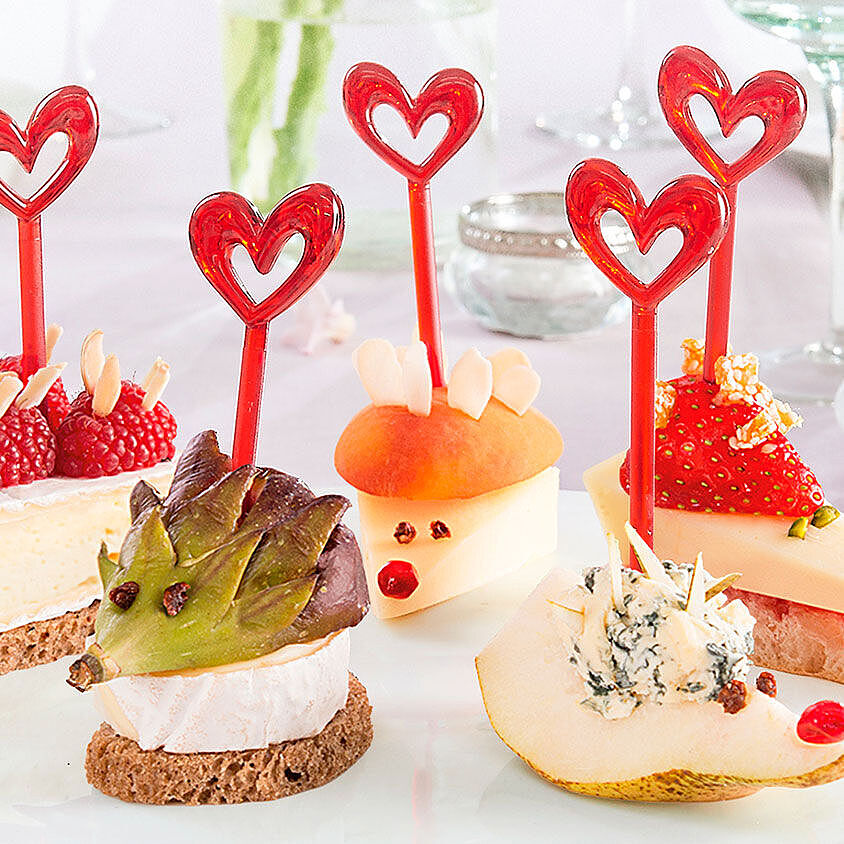 Eine Sammlung liebevoll dekorierter Käseigel aus verschiedenen Käsesorten mit Herzchen-Spießen