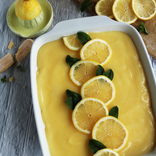 Ein frisch zubereitetes Zitronen-Tiramisu mit Limoncello in einer weißen Auflaufform, garniert mit Zitronenscheiben und Minzblättern.