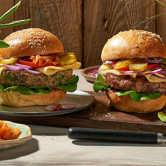 Deftige Cheeseburger belegt mit Salat, Tomate, Zwiebel und würzigen Schnittkäse