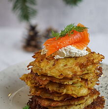 Frisch gebratene Kartoffelpuffer, garniert mit Räucherlachs und BRESSO Wildkräutern, serviert auf einem Teller.