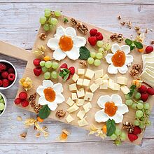 Ein vegetarisches Charcuterie Board mit Frischkäseblumen, Géramont, Fol Epi, frischem Obst und Nüssen – perfekt für Brunch oder Osterfest.