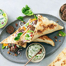 Veganer Döner mit Bohnen-Falafel-Bällchen, frischem Salat und Fladenbrot – dazu ein Schälchen Bresso Frischkäse Tsatsiki