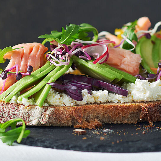 Angerichtetes Avocado-Toast mit Fisch und Sprossen