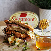 Knusprig geröstetes Croissant-Sandwich mit Géramont, Prosciutto, Honig, Balsamico-Creme und gehackten Pistazien.