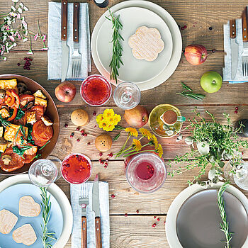 Bunt dekorierter Tisch zum Frühlingsanfang mit Blumen, Obst und Gemüse